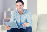 Smiling casual man holding tablet and credit card