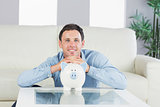 Smiling casual man resting head on piggy bank