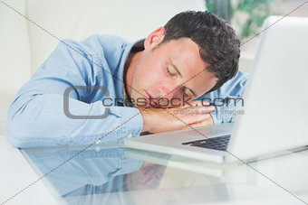 Exhausted casual man sleeping with head resting on table