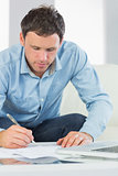 Content casual man writing on sheets paying bills