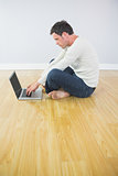 Casual attractive man sitting on floor using laptop