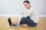 Casual content man sitting on floor using laptop