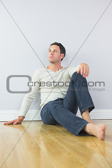 Casual thoughtful man leaning against wall looking up