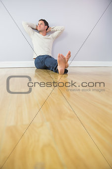 Casual thoughtful man leaning against wall with crossed arms