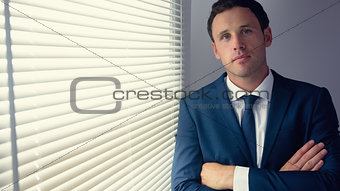 Content handsome businessman standing with crossed arms