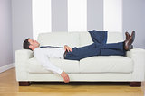 Tired handsome businessman lying on couch