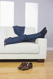 Close up of male legs in suit lying on couch