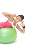 Smiling sporty brunette doing exercise on exercise ball