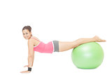 Smiling sporty brunette doing exercise with exercise ball