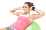 Cheerful sporty brunette doing sit ups on exercise ball