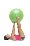 Calm sporty brunette lying on floor holding exercise ball between legs