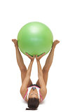 Sporty brunette lying on floor holding exercise ball between legs