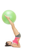 Content sporty brunette holding exercise ball between legs