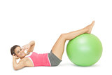 Smiling sporty brunette doing sit ups with exercise ball