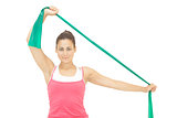 Cheerful sporty brunette stretching with resistance band