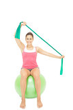 Gleeful sporty brunette stretching with resistance band