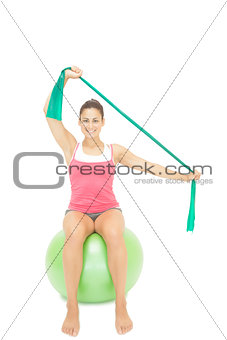 Gleeful sporty brunette stretching with resistance band