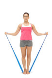 Serious sporty brunette exercising with resistance band