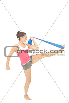 Calm sporty brunette exercising with resistance band