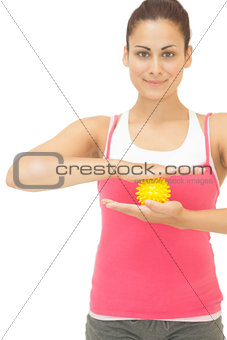 Smiling sporty brunette holding yellow massage ball