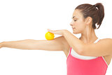 Peaceful sporty brunette touching arm with yellow massage ball