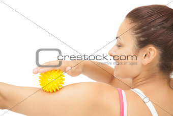 Cheerful sporty brunette touching arm with yellow massage ball