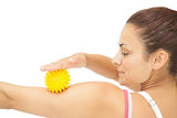 Calm sporty brunette touching arm with yellow massage ball