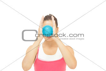 Toned brunette holding blue massage ball between hands