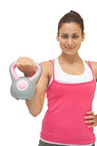 Smiling sporty brunette holding grey and pink kettlebell