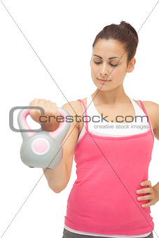 Content sporty brunette holding grey and pink kettlebell