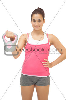 Happy sporty brunette holding grey and pink kettlebell