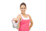 Cheerful sporty brunette holding grey and pink kettlebell