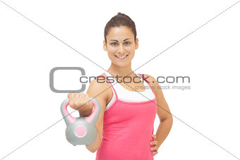 Cheerful sporty brunette holding grey and pink kettlebell