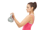 Attractive sporty brunette holding grey and pink kettlebell