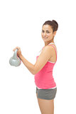 Pretty sporty brunette holding grey and pink kettlebell