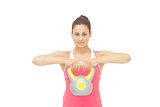 Smiling sporty brunette holding grey and yellow kettlebell