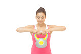 Content sporty brunette holding grey and yellow kettlebell