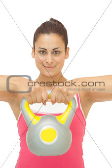 Happy sporty brunette holding grey and yellow kettlebell
