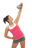 Happy sporty brunette holding grey and kettlebell
