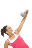 Cheerful sporty brunette holding grey and kettlebell
