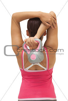 Rear view of sporty brunette holding kettlebell