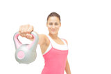 Smiling toned brunette showing grey and pink kettlebell