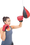 Stern sporty brunette training with punching bag
