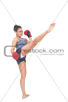 Stern sporty brunette kicking in the air