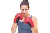 Serious sporty brunette wearing red boxing gloves