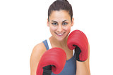 Smiling sporty brunette wearing red boxing gloves