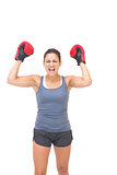 Excited sporty brunette wearing red boxing gloves