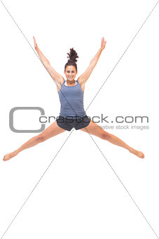 Smiling sporty brunette jumping in the air