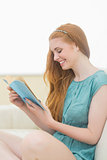 Happy redhead reading a book on the sofa