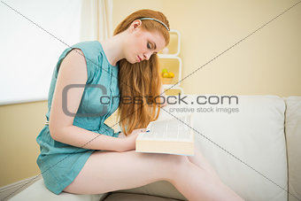 Pretty redhead reading a book on the couch